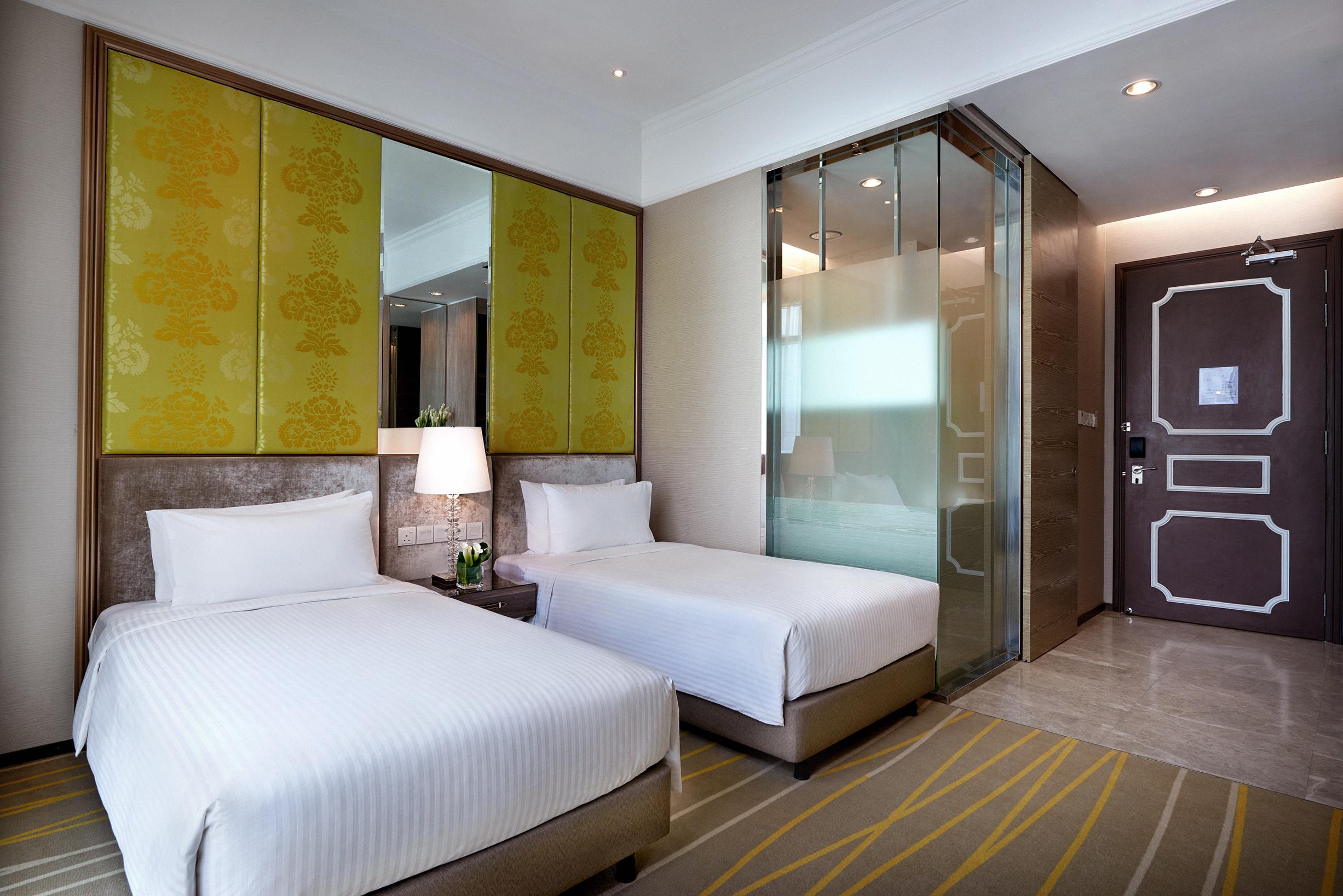 Hotel Dorsett Putrajaya Exteriér fotografie The photo shows a modern hotel room with two twin beds dressed in white linens. There are stylish headboards behind each bed, complemented by vibrant yellow panels on the wall. A glass partition is visible, likely leading to a bathroom area, which ad