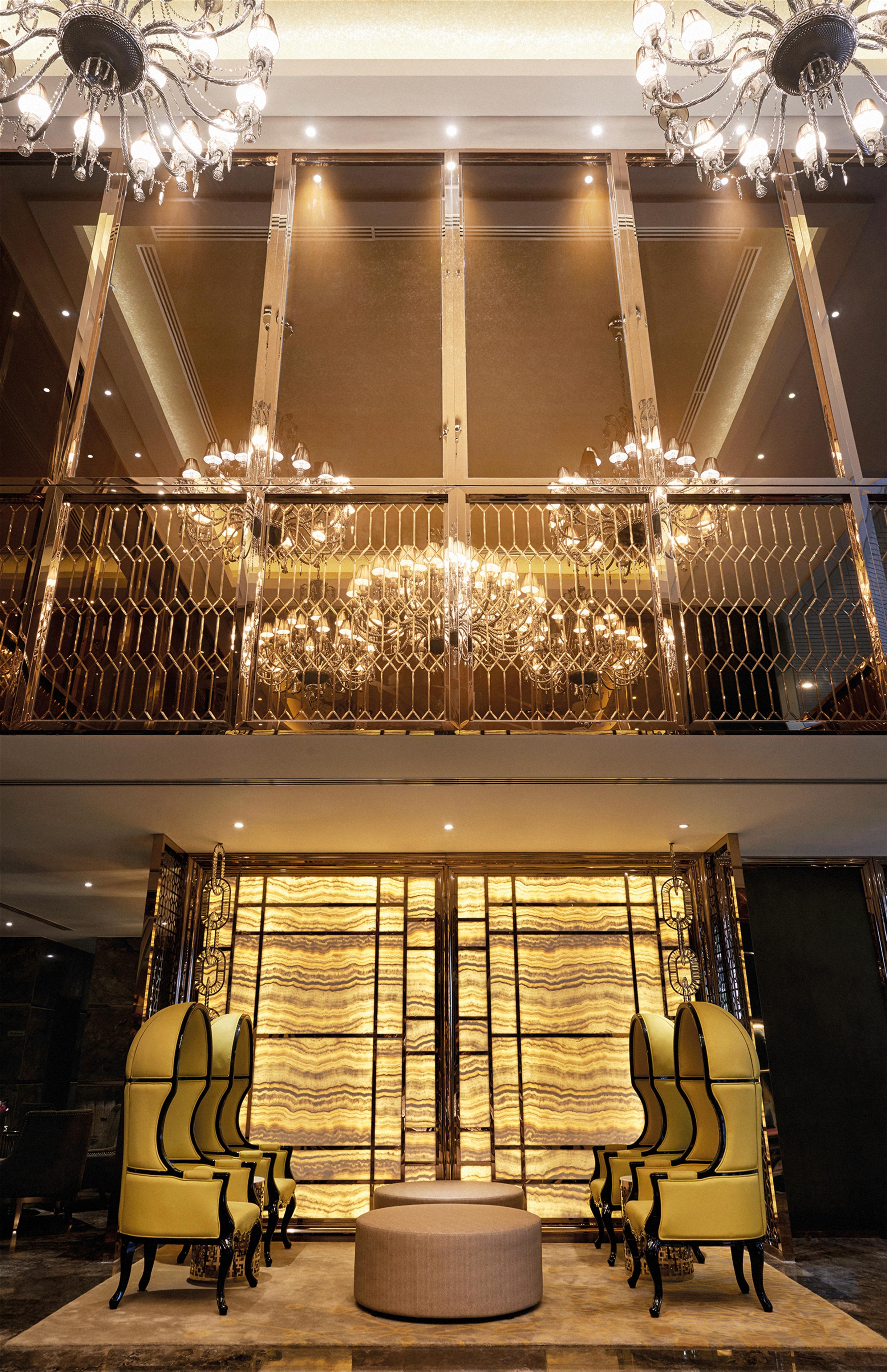 Hotel Dorsett Putrajaya Exteriér fotografie The photo shows an elegant interior space featuring multiple chandeliers hanging from a balcony or upper level. The chandeliers emit a warm glow, creating a luxurious atmosphere. Below, there is a decorative wall, possibly made of stone or a similar 