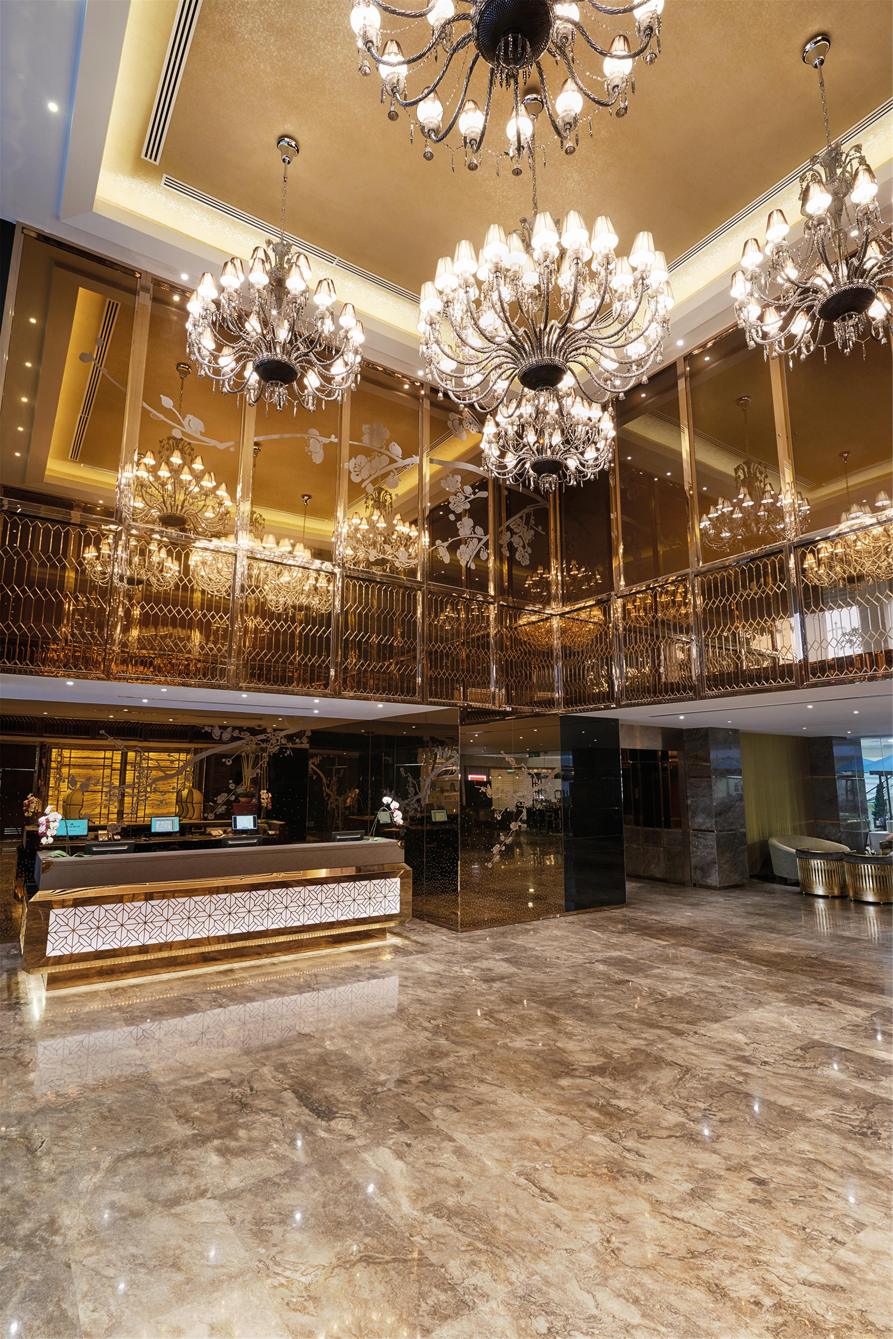 Hotel Dorsett Putrajaya Exteriér fotografie The photo shows a luxurious hotel lobby interior. It features a grand design with golden accents and elegant chandeliers hanging from the ceiling. The reception area has a stylish desk with decorative details, and the surrounding space is adorned wit