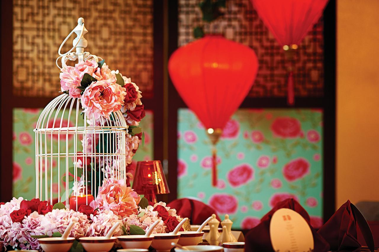 Hotel Dorsett Putrajaya Exteriér fotografie The photo shows a beautifully decorated table setting with an elaborate centerpiece. The centerpiece features a white birdcage adorned with pink and red flowers. Surrounding the birdcage are additional floral arrangements that complement the colors. 