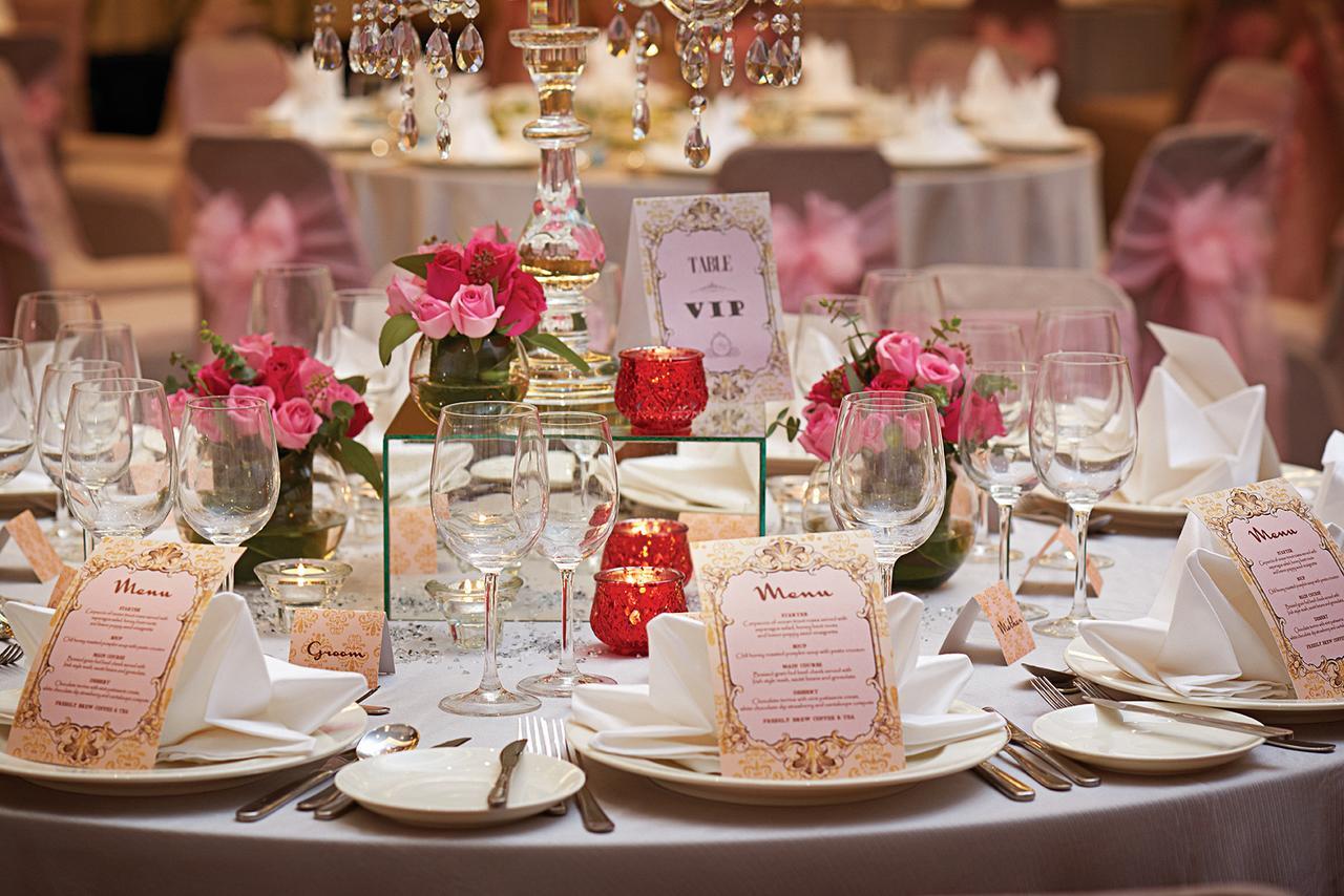 Hotel Dorsett Putrajaya Exteriér fotografie The photo depicts an elegantly set dining table for a formal event or celebration. The table is beautifully adorned with various decorative elements:

1. **Table Setting**: The tablecloth is likely white or light-colored, with neatly arranged plates,