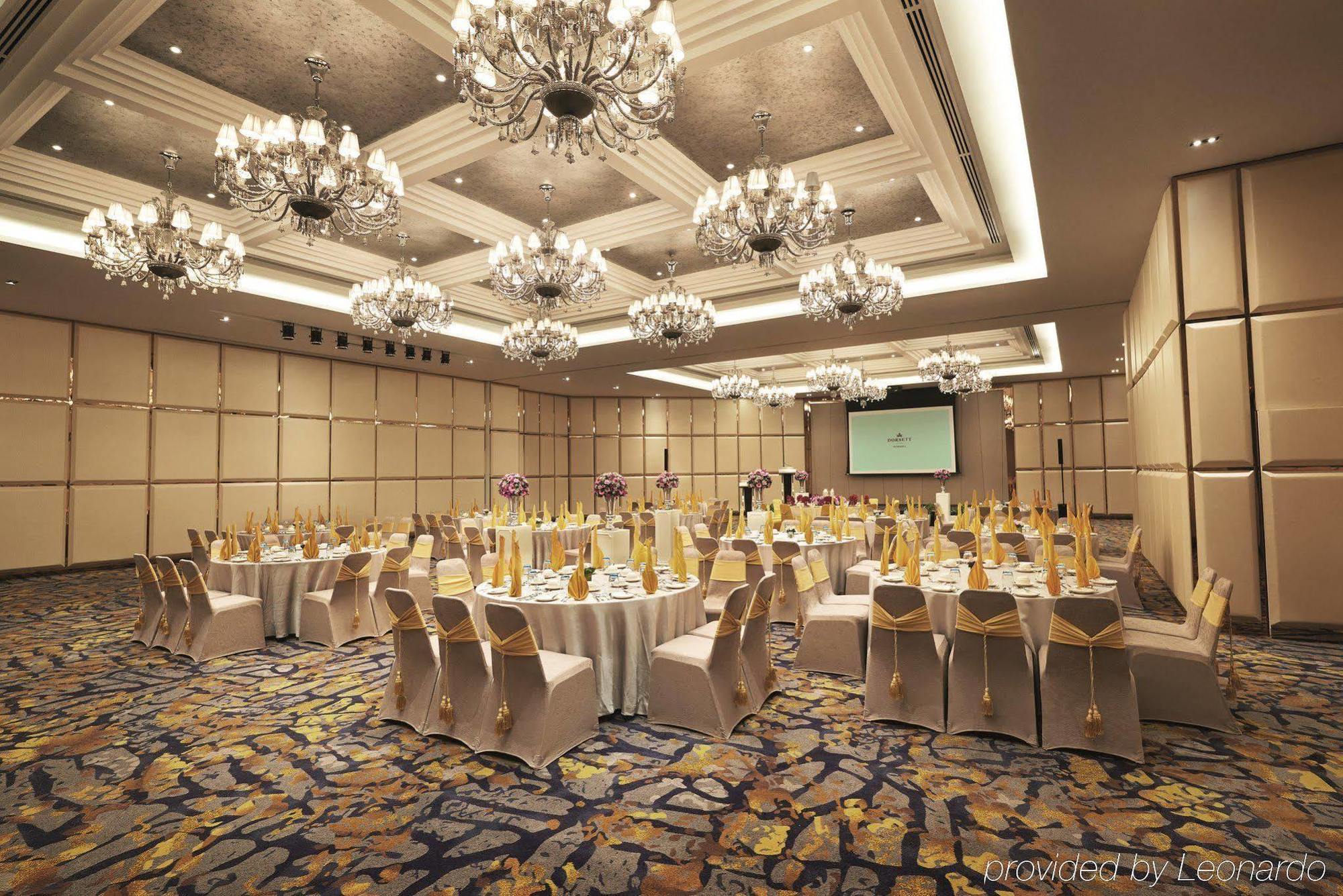 Hotel Dorsett Putrajaya Exteriér fotografie The photo depicts an elegant banquet or conference room setup. It features multiple round tables, each covered with white tablecloths and adorned with gold decorations, suggesting a formal event. The chairs are also draped with golden sashes. The roo