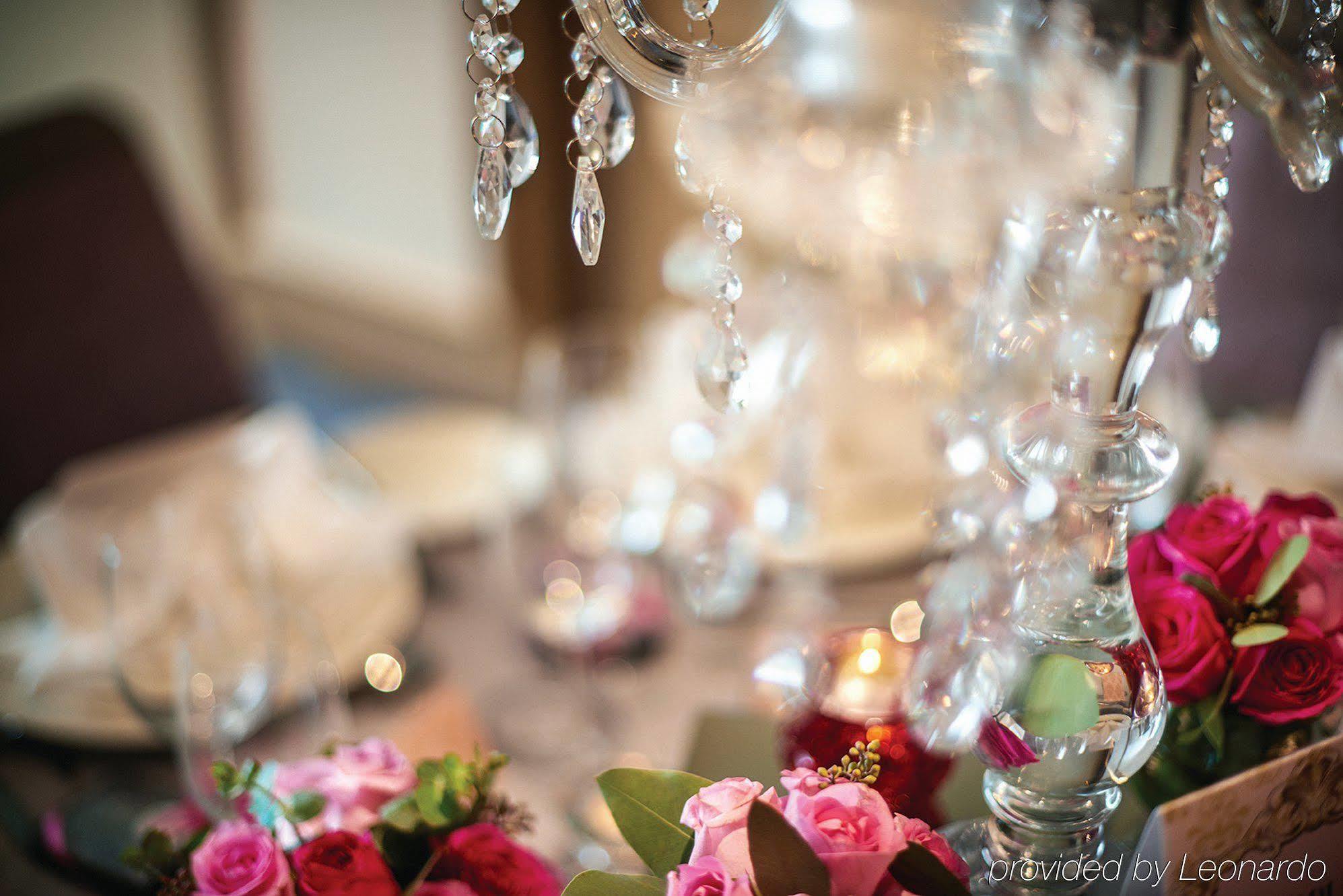 Hotel Dorsett Putrajaya Exteriér fotografie The photo features a beautifully set dining table with an elegant centerpiece. The centerpiece is a chandelier adorned with hanging crystals, reflecting light. Surrounding the chandelier are vibrant floral arrangements, primarily consisting of pink r