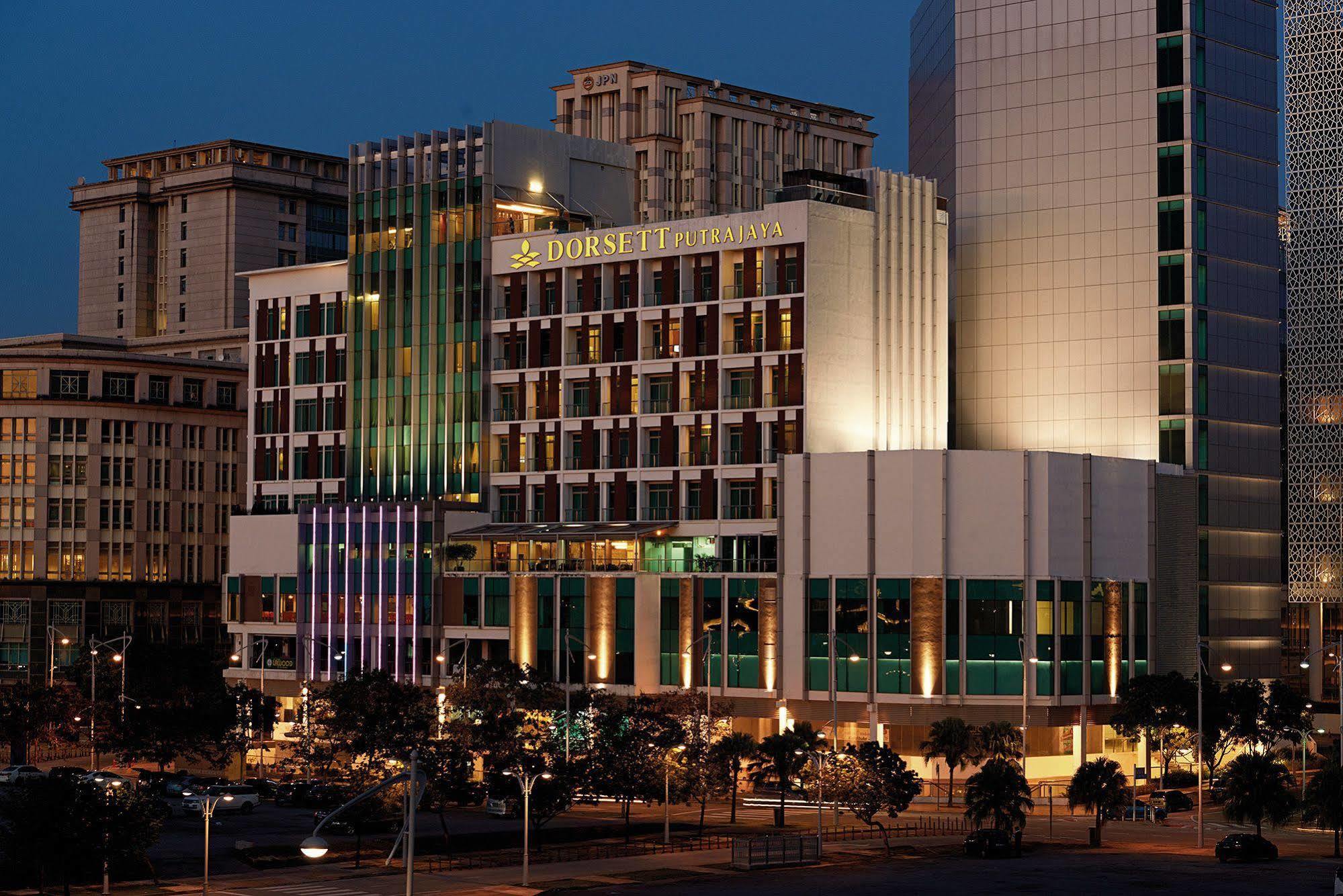 Hotel Dorsett Putrajaya Exteriér fotografie The image shows a modern hotel building illuminated at night. The structure features a combination of glass and concrete materials, with a façade that has various colors and textures. The hotel appears to have multiple stories and is situated in an u