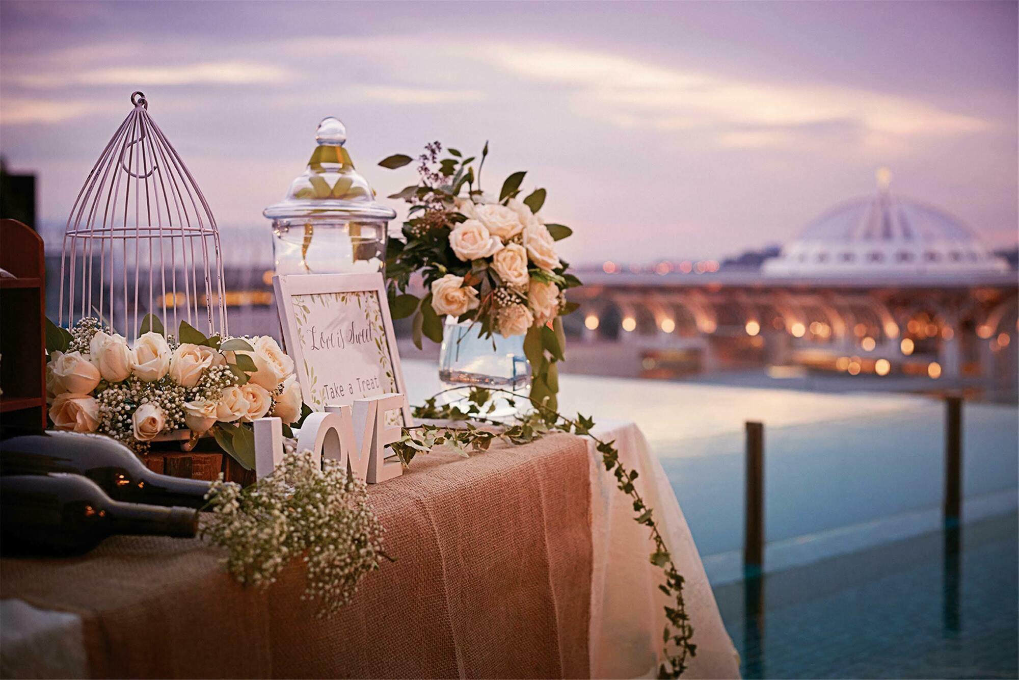 Hotel Dorsett Putrajaya Exteriér fotografie The photo depicts a beautifully arranged outdoor setting with a table elegantly decorated for an event, possibly a wedding or special occasion. 

- **Floral Arrangements**: There are various floral arrangements, including soft-colored roses and green